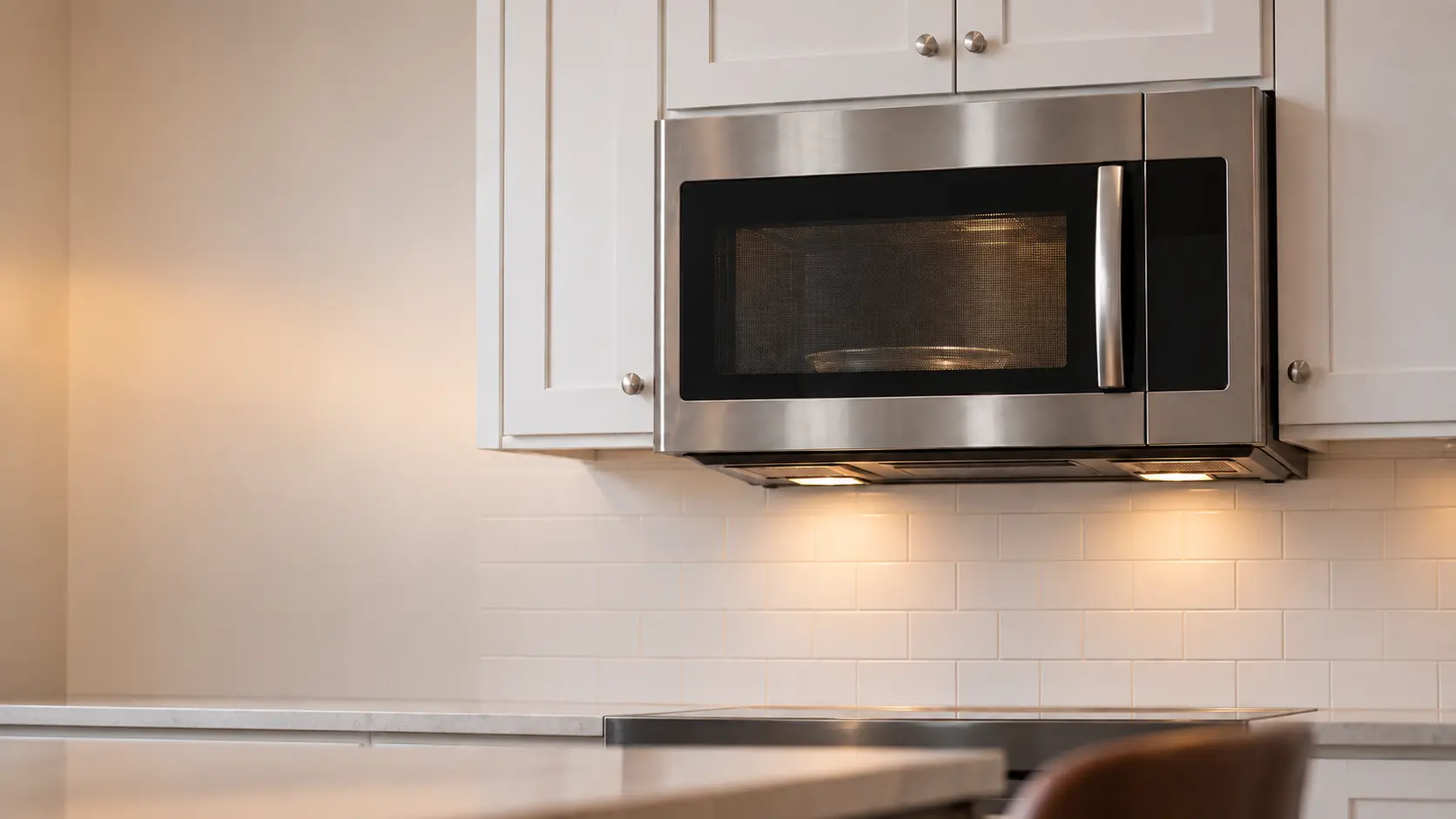 A stainless microwave hood combination set between two white wall cabinets.